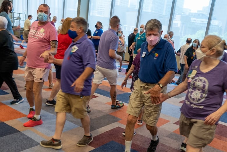 A group of people square dance together in a hotel ballroom.