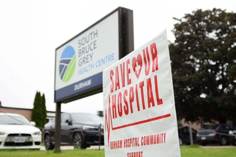 A lawn sign that says "save our hospital" is set up in front of the hospital's sign that reads "South Bruce Grey Health Centre - Durham"