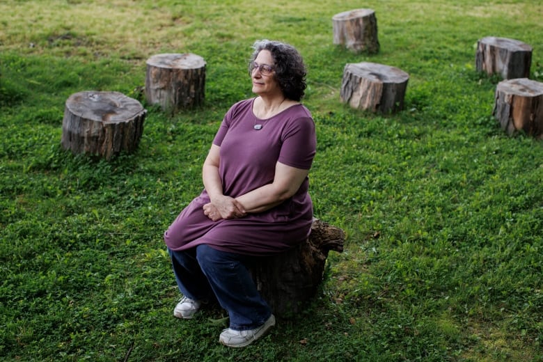 woman sits on stump