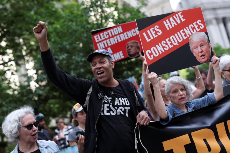 Anti-Trump demonstrators hold placards outside Manhattan criminal court.