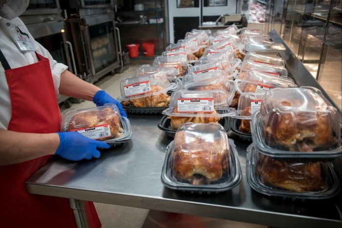 Costco worker preparing cooked chickens