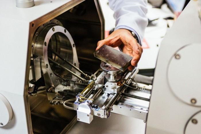 An employee places a sample of kimberlite rock into an electron microscope in a laboratory, operated by De Beers SA, in Johannesburg, South Africa