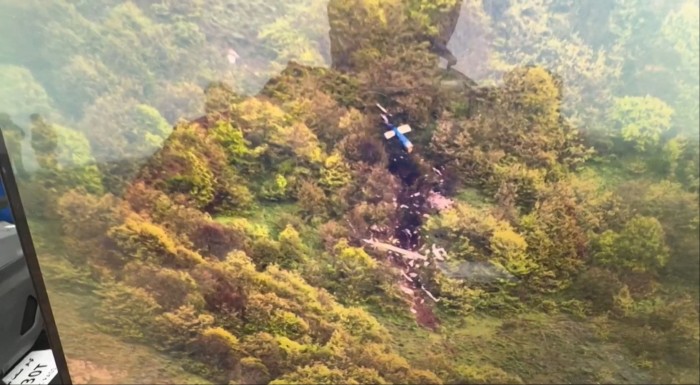 Wreckage from a helicopter is scattered among greenery