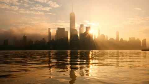 The sun rises behind the skyline of lower Manhattan