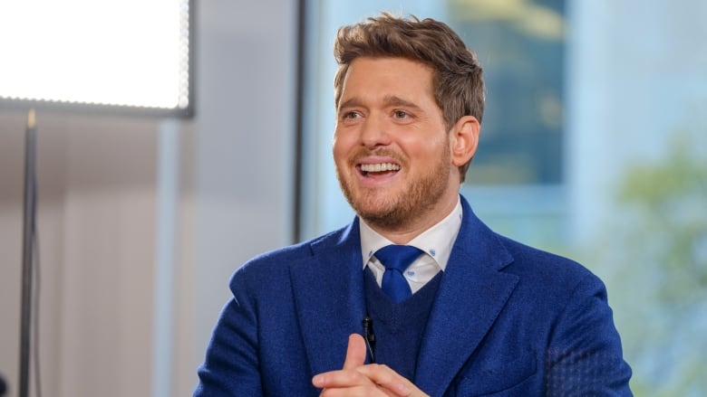 A smiling man wearing a blue suit is shown. 