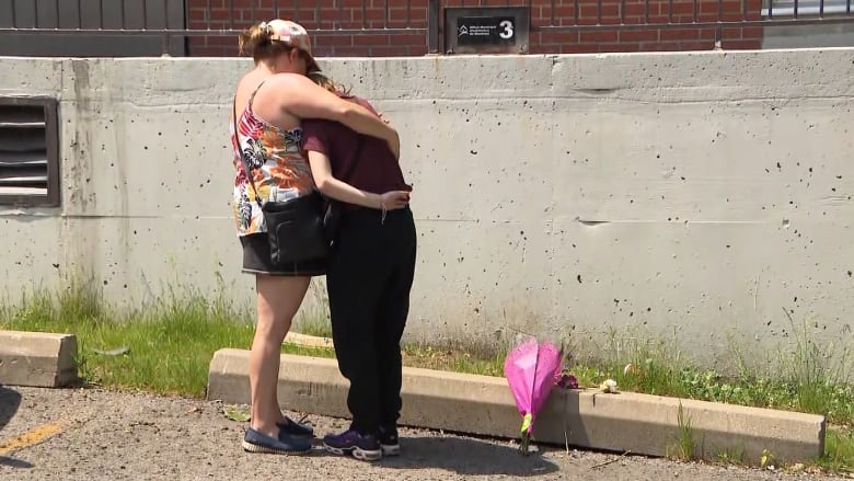 two women hug in a parking lot