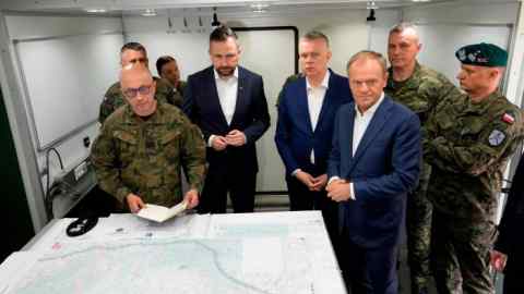 Poland’s Prime Minister Donald Tusk, foreground right, Defense Minister Władysław Kosiniak-Kamysz, centre, and Interior Minister Tomasz Siemoniak, centre right,  visit troops, in Dubicze Cerkiewna