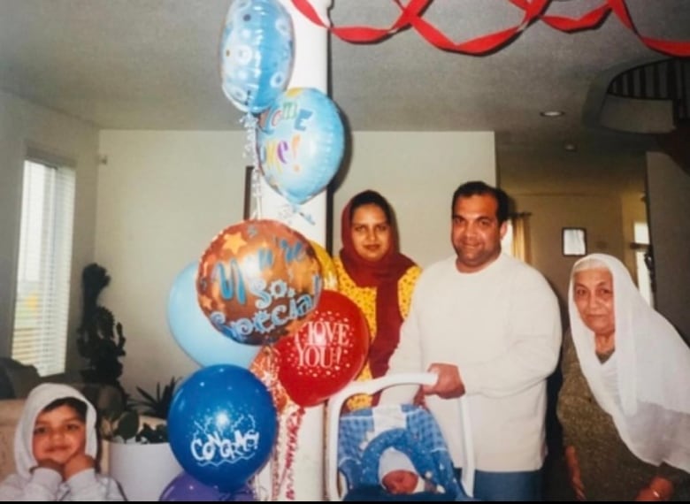 An old family photo depicts a young Vivek standing in front of balloons alongside his parents, grandma, and baby brother. 