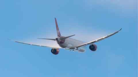 A commercial airplane takes flight amid clear blue skies