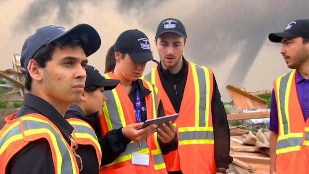 5 members of the Northern Tornadoes Project make observations among the rubble of a house hit by a tornado