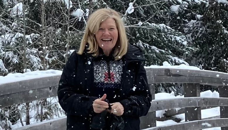 A woman stands outside in a snowy landscape.