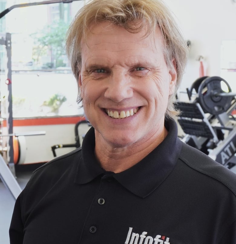 A man stands in a gym, smiling for the camera 