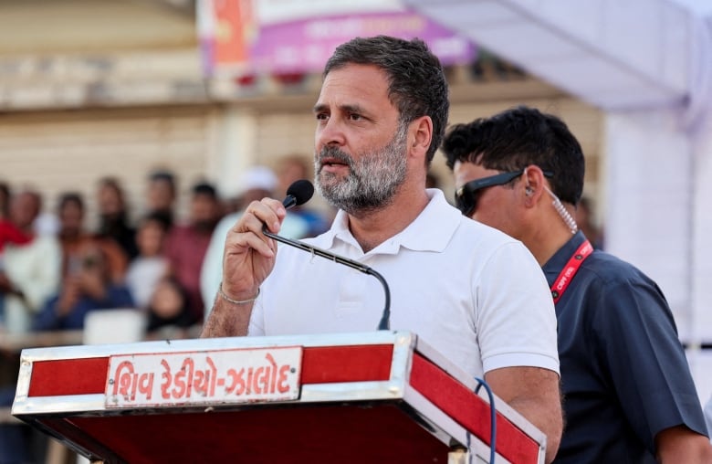 A man in a white shirt speaks at a podium.