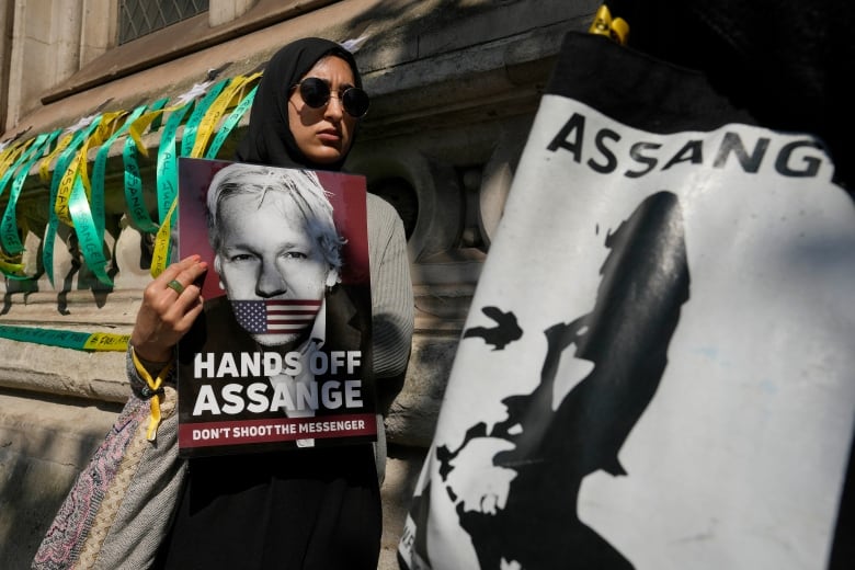 A protester holds placards outside a courthouse. 