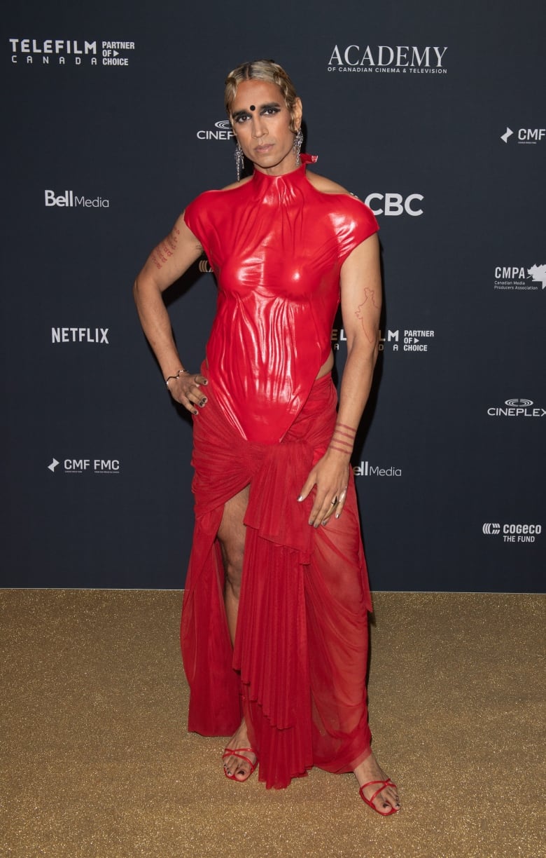 Vivek Shraya on the Canadian Screen Awards red carpet wearing a fitted red dress. 