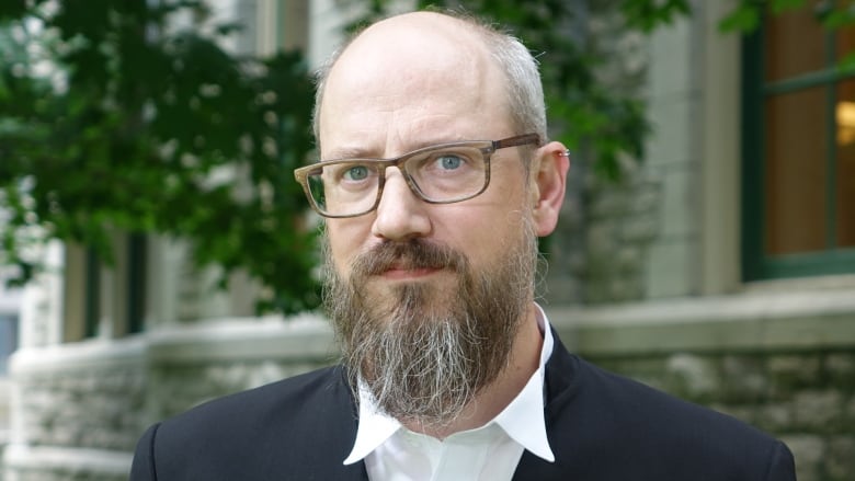 A man with glasses and a beard poses for a photo.