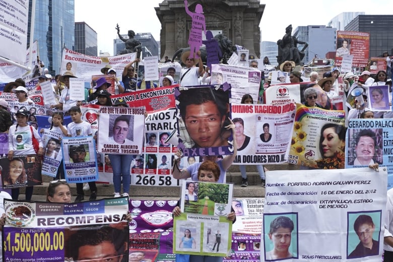 A group of mothers holding pictures of their children march in a demonstration.