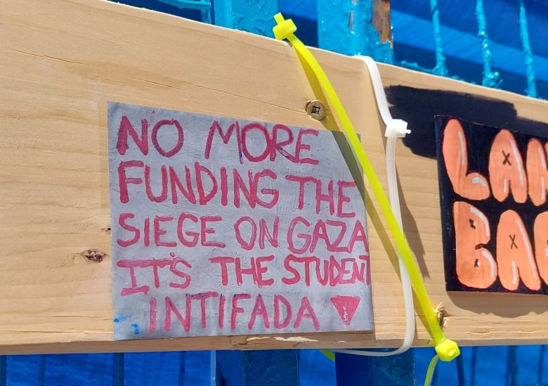 A sign that says: "no more funding the siege on gaza. It's the student intifada." And a red triangle symbol.