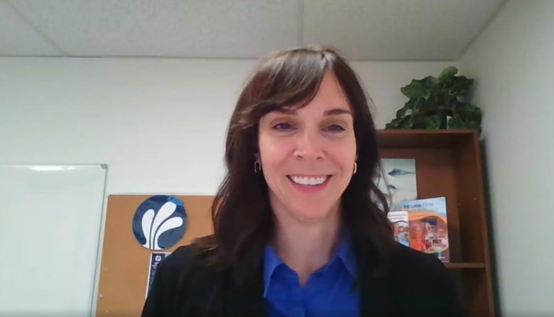 A woman standing in an office smiles.