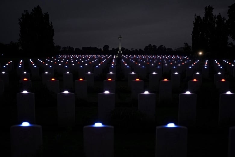 Rows of lights are seen on the ground at night, with a pole-shaped monument visible off in the distance.