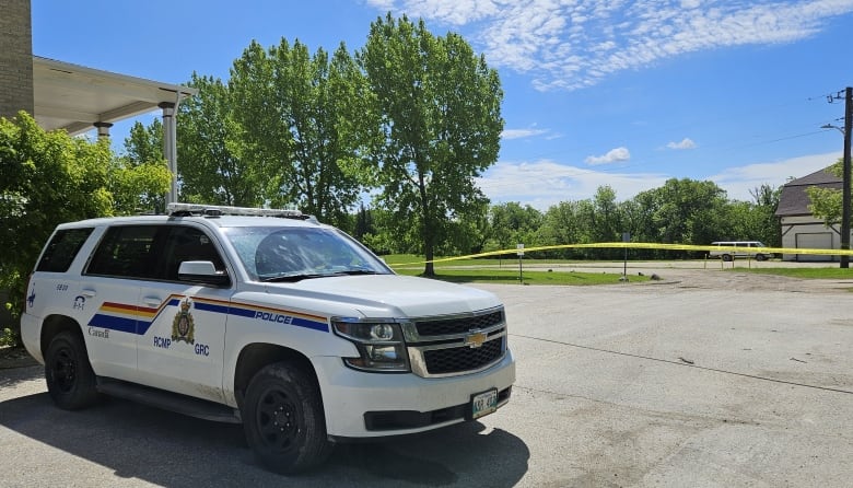 A police cruiser, with police tape behind it.