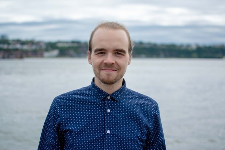 A portrait of a researcher standing in front of a river.