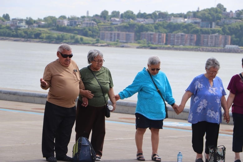 A group of people bow their heads and stand hand-in-hand