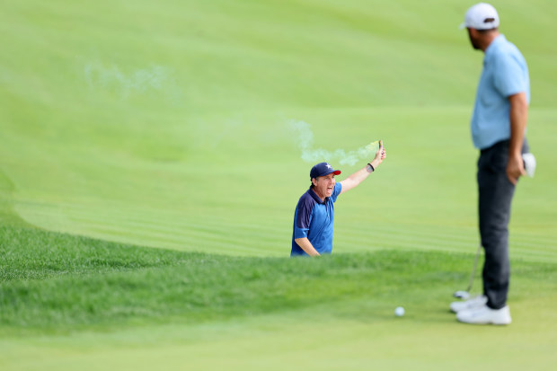 Climate change protestors rush the 18th green as Scottie Scheffler looks on.