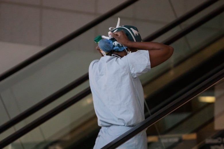 A healthcare worker in scrubs, pictured from the back, adjusts her mask at Surrey Memorial Hospital.