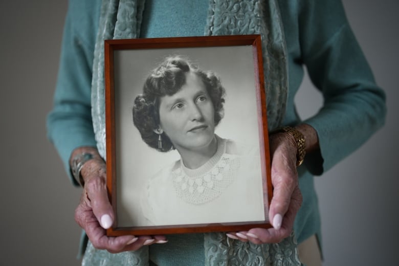 Vi Roden holds a photo of herself when she was 17 years old. The photo shows a girl with short hair and a white top.