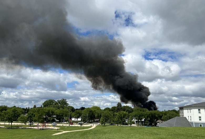 A column of black smoke in the distance from a fire 