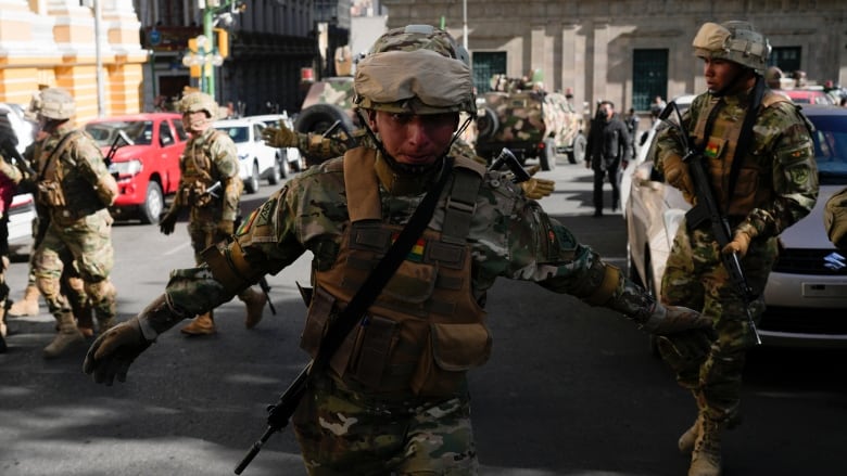 A soldier gestures for journalists to leave Plaza Murillo as soldiers gather near the presidential palace in Plaza Murillo in La Paz, Bolivia.