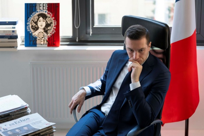 Jordan Bardella in his office with a French flag in the background