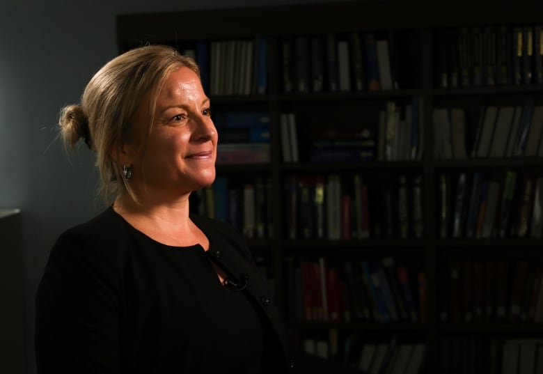 A woman with pulled back blond hair looks off camera. 