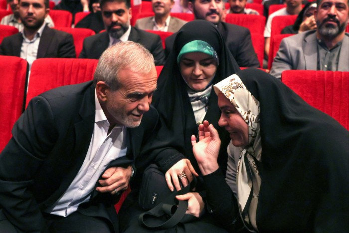 Masoud Pezeshkian sitting next to his daughter as he listens to a woman talking to him