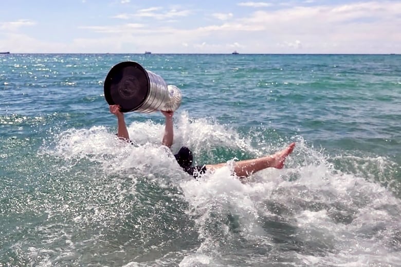 A  man  holds a trophy in the ocean