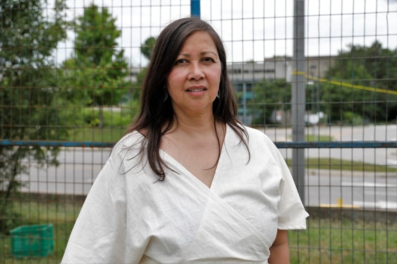 A person standing in front of a fenced-off building.