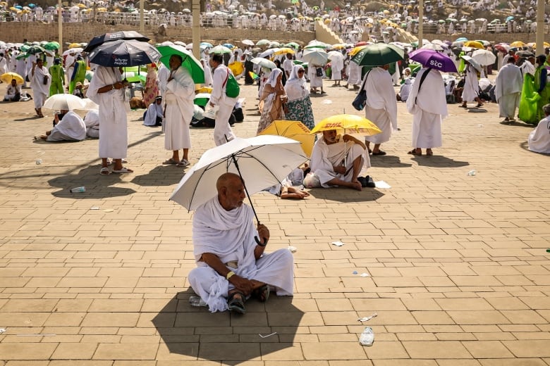 Muslim pilgrims use umbrellas to shade themselves from the sun as they arrive at the base of Mount Arafat, also known as Jabal al-Rahma or Mount of Mercy, during the annual hajj pilgrimage on June 15, 2024. 