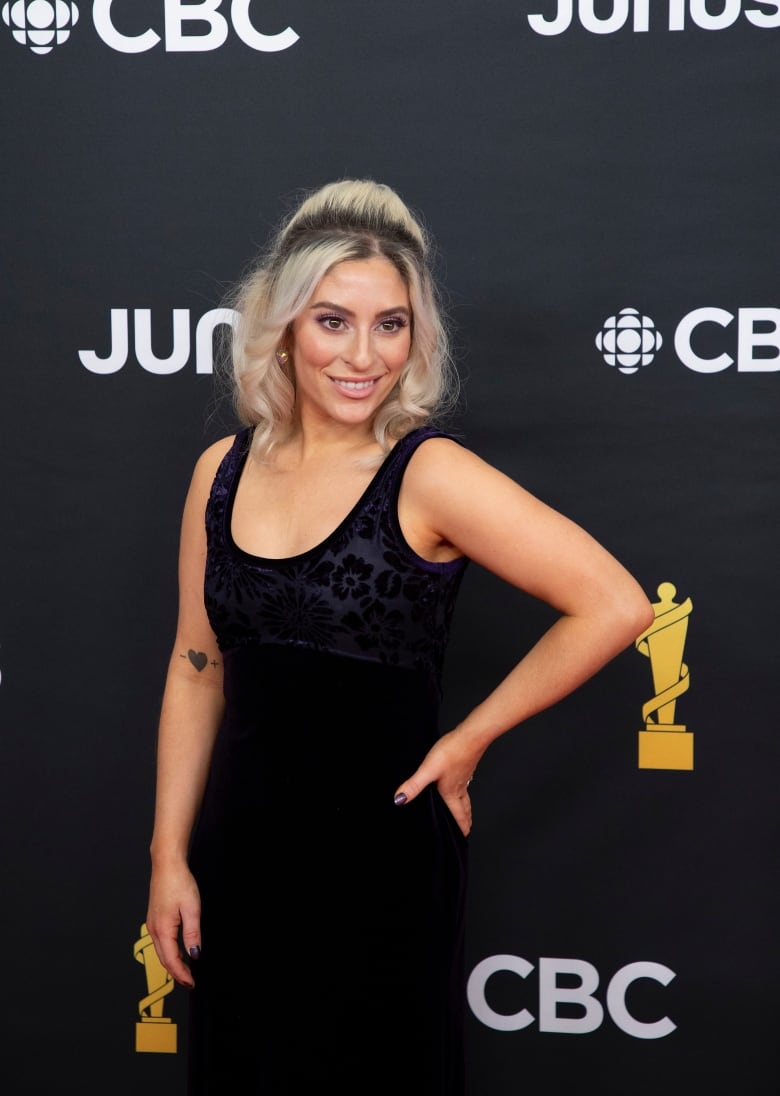 A woman in a black dress poses for cameras.