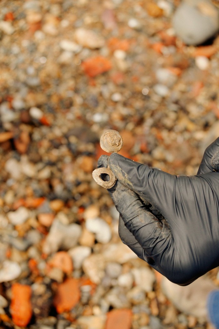 A gloved hand holds a tiny rusted metal object