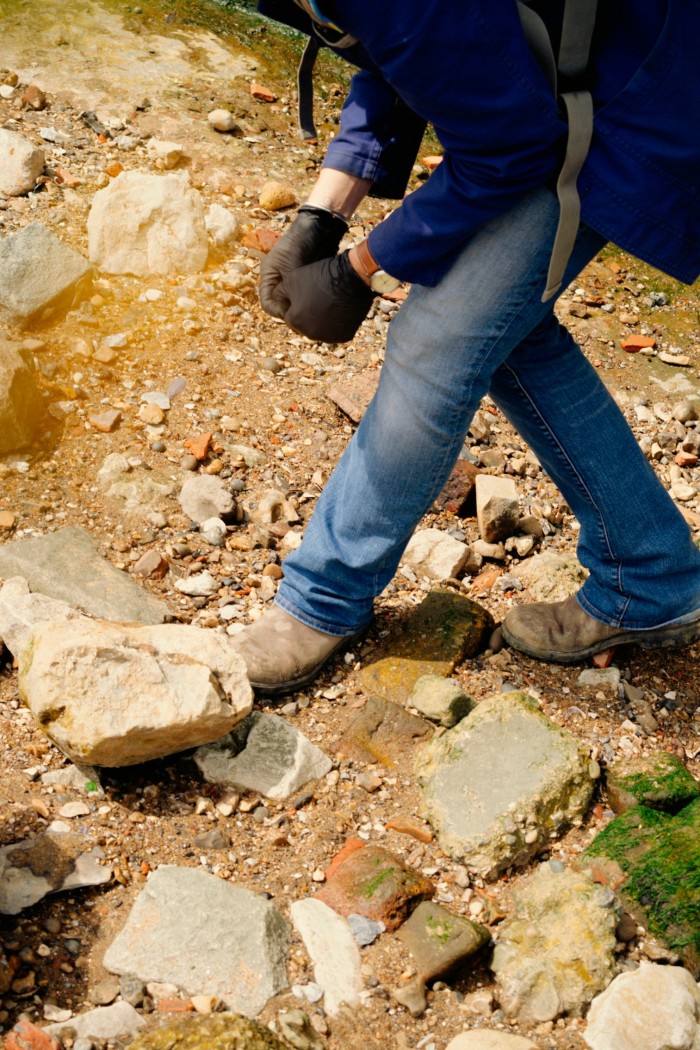 A pair of legs in jeans steps carefully among the detritus