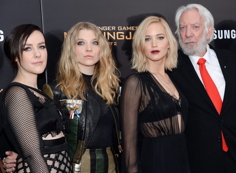 Four actors dressed in formal wear — three woman and one man — attend a movie premiere. Donald Sutherland is on the far right of the photo.
