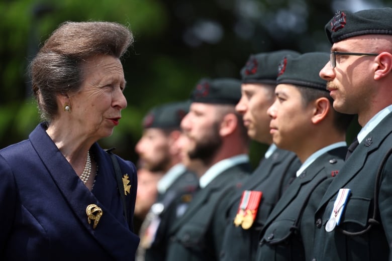 A person talks with soldiers standing in a row.