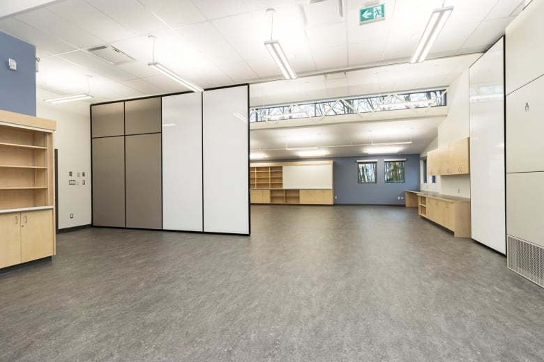 The interior of a bright classroom with high ceilings and a movable dividing wall. 