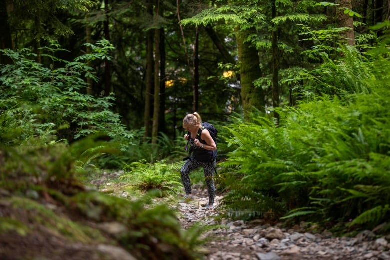 A blonde woman hikes up a steep trail.