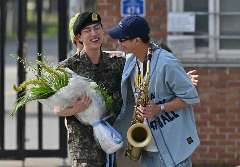 K-pop boy band BTS member Jin (left, in uniform) is greeted by bandmade RM, outside a military base in Yeoncheon, South Korea.