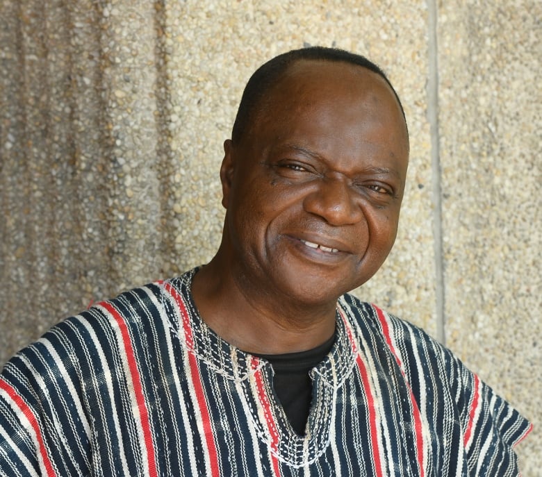 A man wearing a dashiki smiles in a portrait. 