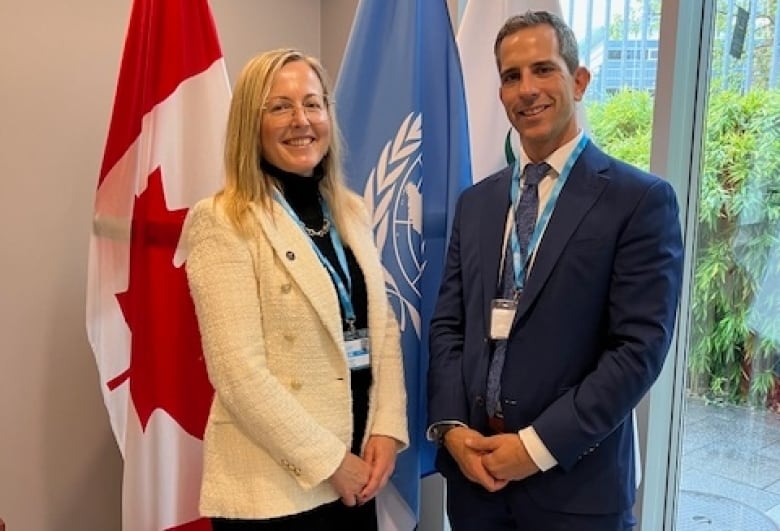 The doctors stand in front of the United Nations flag and the Canadian Flag.