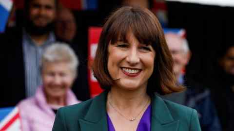 A woman in a green suit smiles for the camera