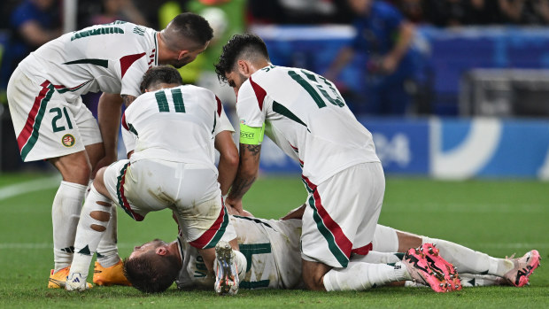 Barnabas Varga of Hungary lies on the ground and is assisted by teammates after a collision with goalkeeper Angus Gunn of Scotland.